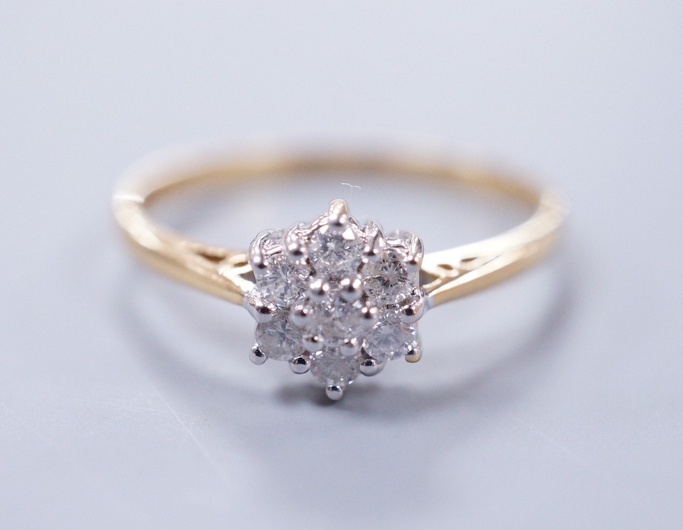 A modern 18ct gold and seven stone diamond set flower head cluster ring, size P, gross weight 2.4 grams